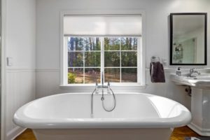 A sink and a white tub sitting next to a window